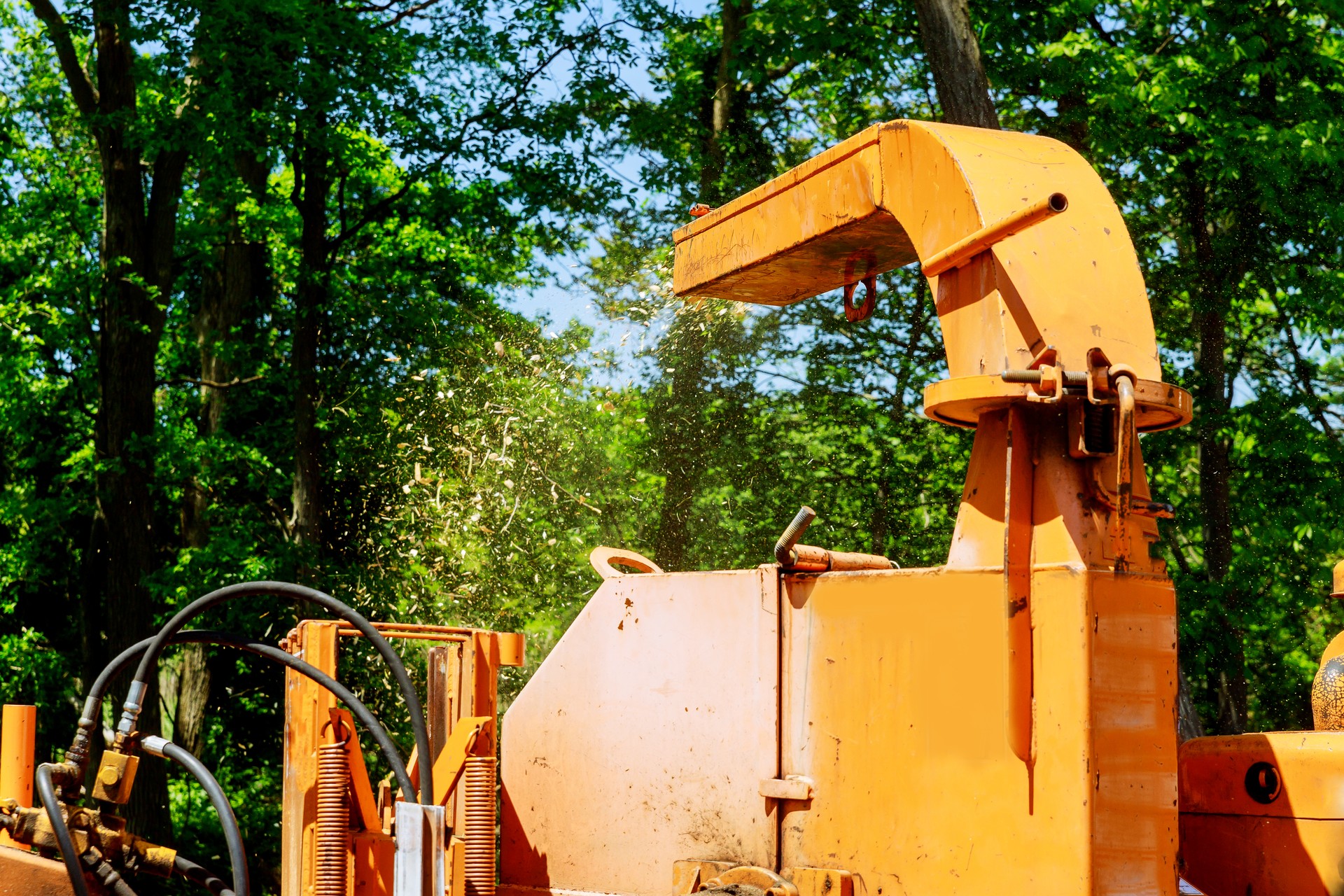 Landscapers using chipper machine to remove and haul chainsaw tree branches